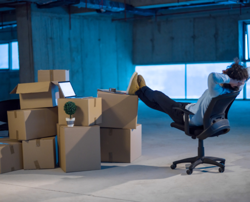 Photo d'un homme dans son entrepôt. Il fait la sieste les pieds posés sur les cartons de nombreuses marchandises.
